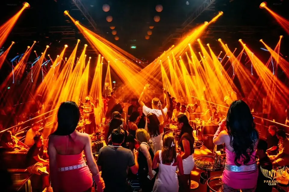 Tia đèn moving head cam vàng toả kín trần Paradise Club Nha Trang, khách giơ tay giữa sàn