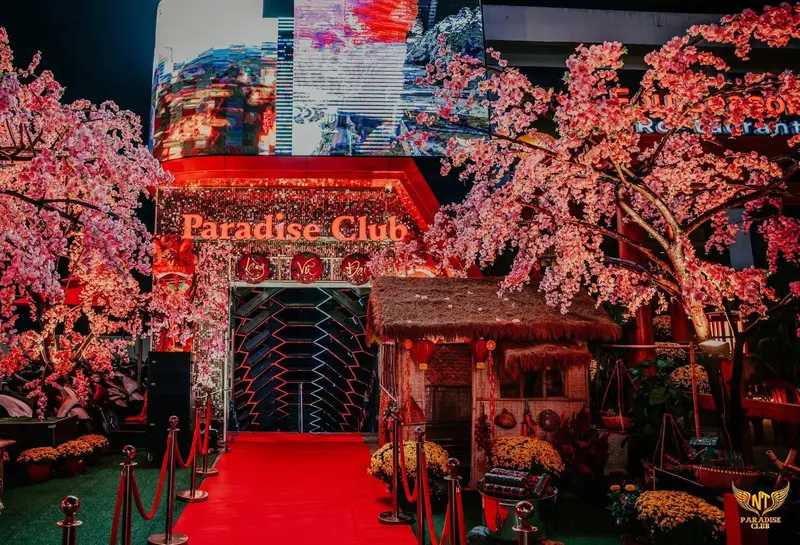Lối vào Paradise Club Nha Trang với thảm đỏ, biển tên phát sáng và hoa anh đào trang trí