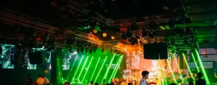 Laser xanh lá quét dưới giàn đèn trên sân khấu Paradise Club
